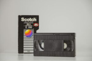 Retro VHS cassette with box in studio setting, representing nostalgia and vintage media.